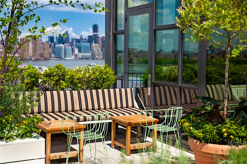 A bench surrounded by potted plants on a rooftop bar in New York City