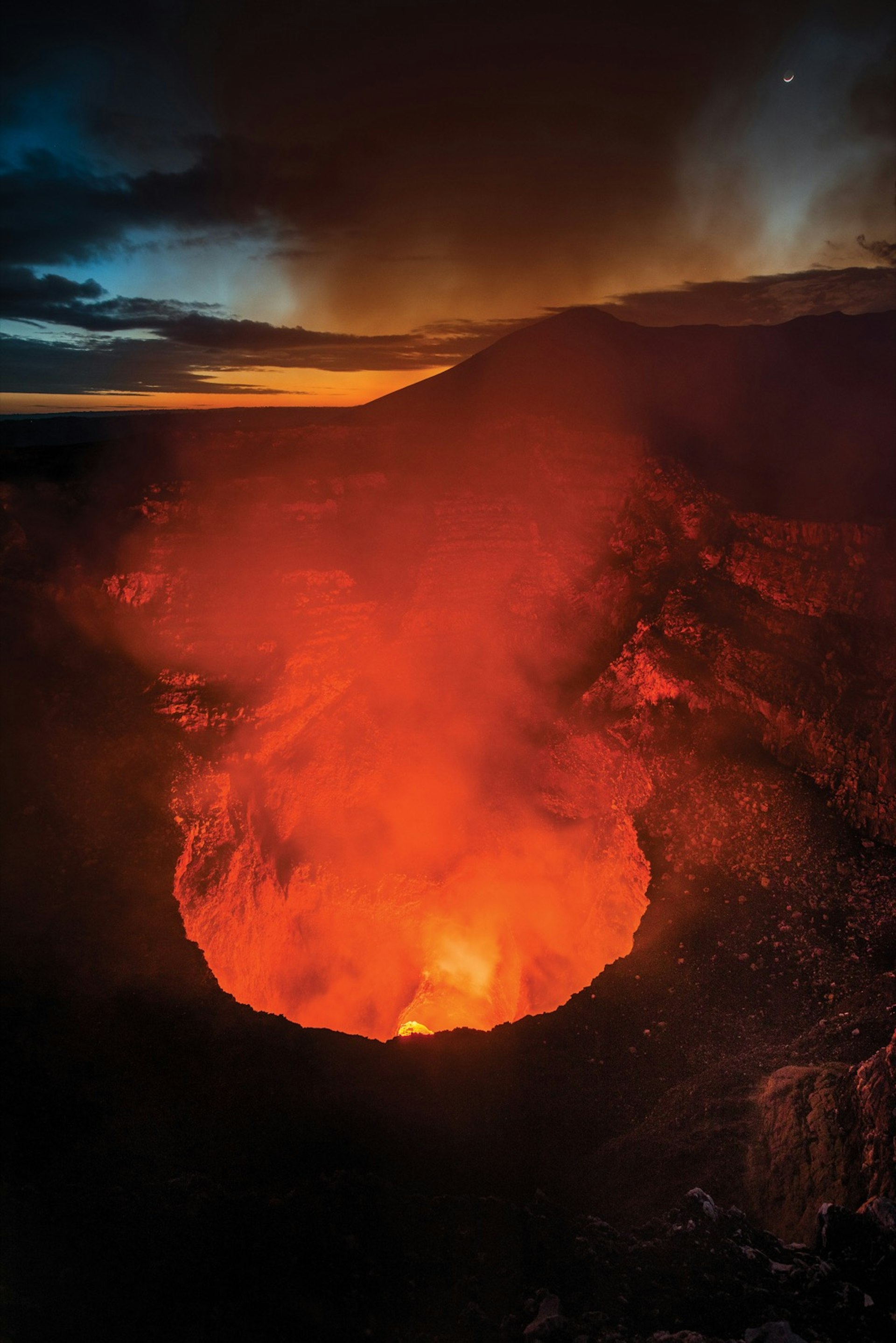 Orange lava spews and white steam rises from the top of Masaya Volcano at night. Nicaragua travel offers chances to explore the country's rich landscape. 