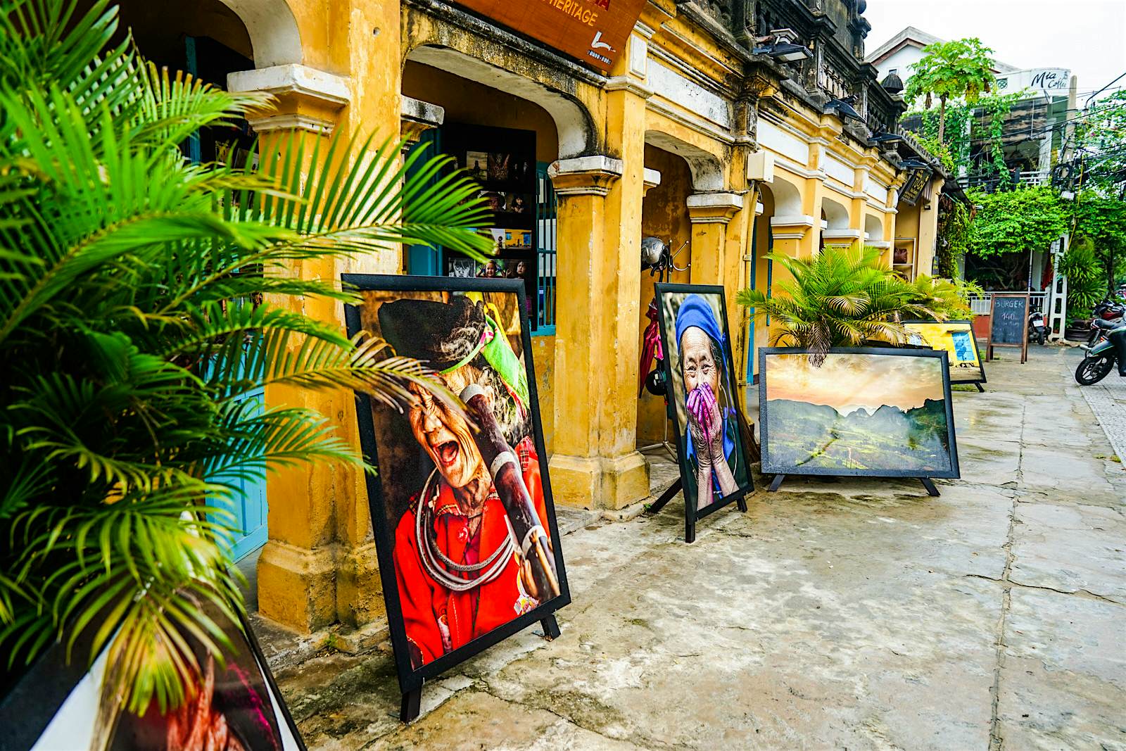 Large paintings of women in traditional dress sit either side of a yellow archway leading to a shop entrance