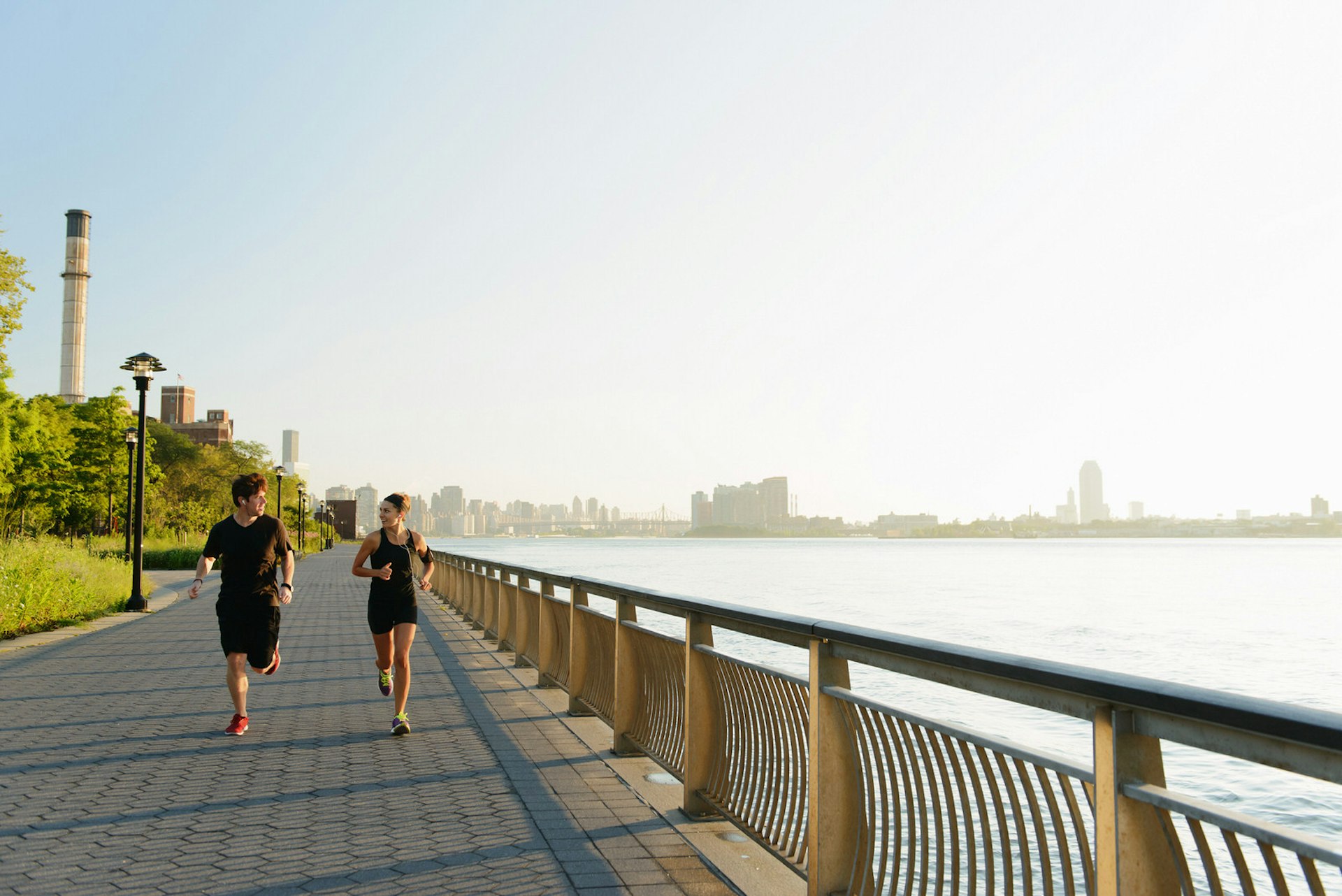Two runners run along the footpath next to the Hudson River in New York City at twilight