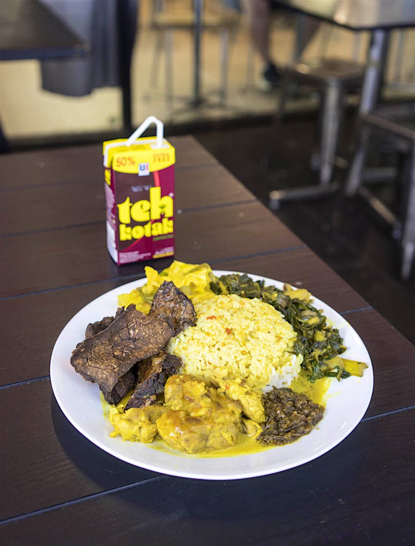 Features - Salero-Kito-in-Melbourne-Padang-food-Sofia-Levin-2.jpg-4c37a11c02c0 Salero Kito, Padang food, in Melbourne. The dish is served on a dark wooden table alongside a carton of juice. There is rice, brown meat, sauce and green vegetables on the plate.