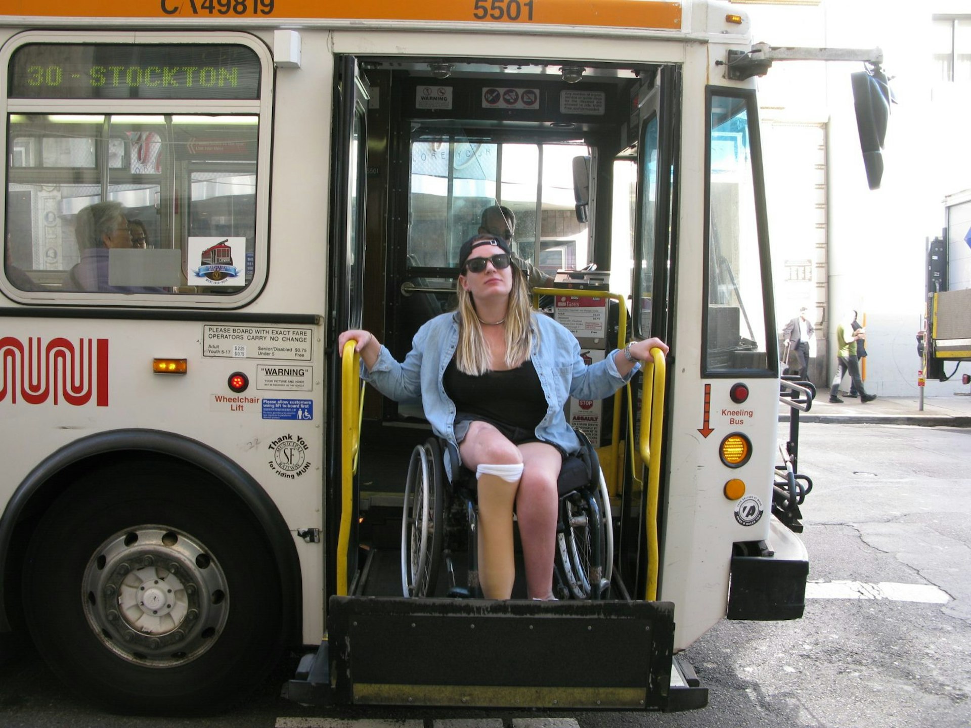 A woman in a wheelchair is alighting from a bus.