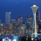 The skyline of seattle is seen in early evening, with lights on the space needle and various other buildings. Perfect weekend in Seattle