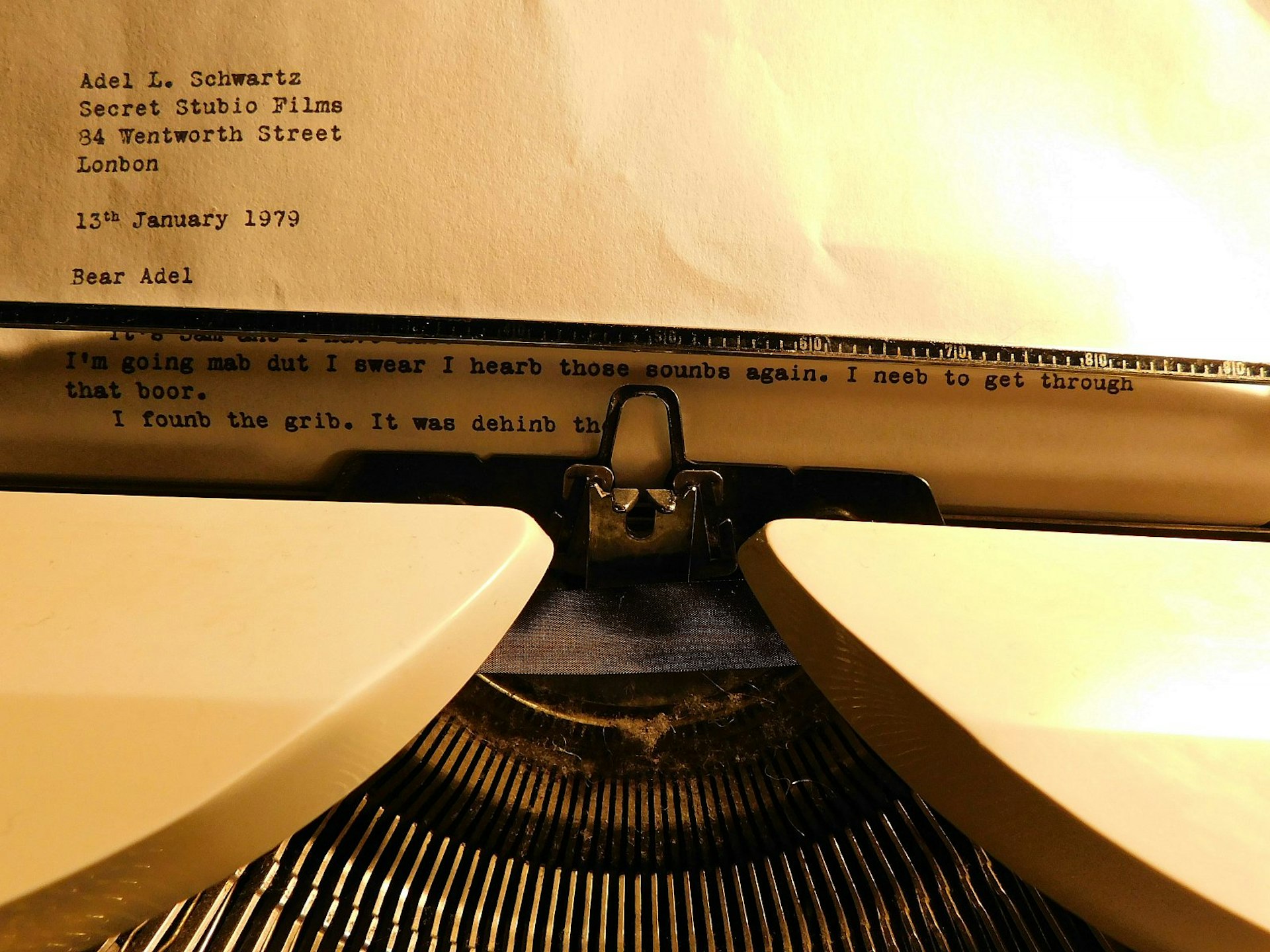 A close-up of a mysterious letter protruding from an old-fashioned typewriter; in the letter all instances of the letters d and b have been swapped around.