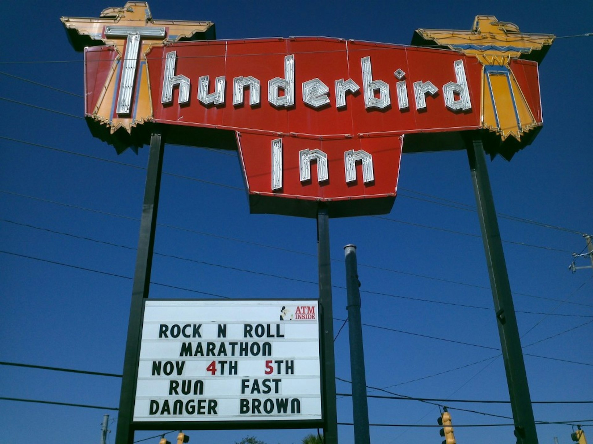 A neon sign reading "Thunderbird Inn," with a blue sky behind