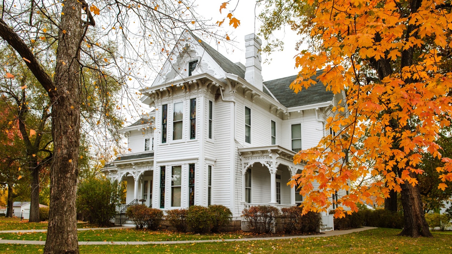 The white facade of the Truman House surrounded by orange leaves; historic homes