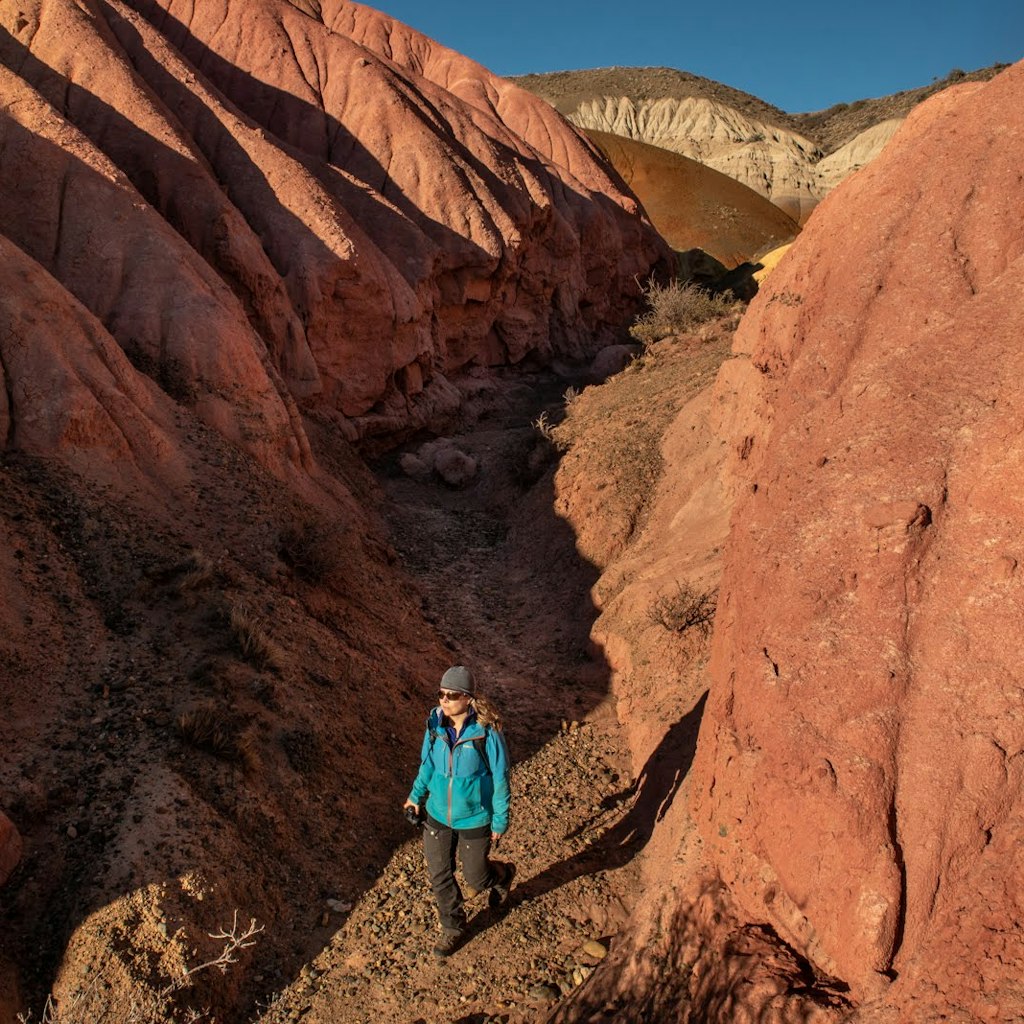 A hiker surrounded by a short canyon of red rock walls in Argentina's Patagonia National Park