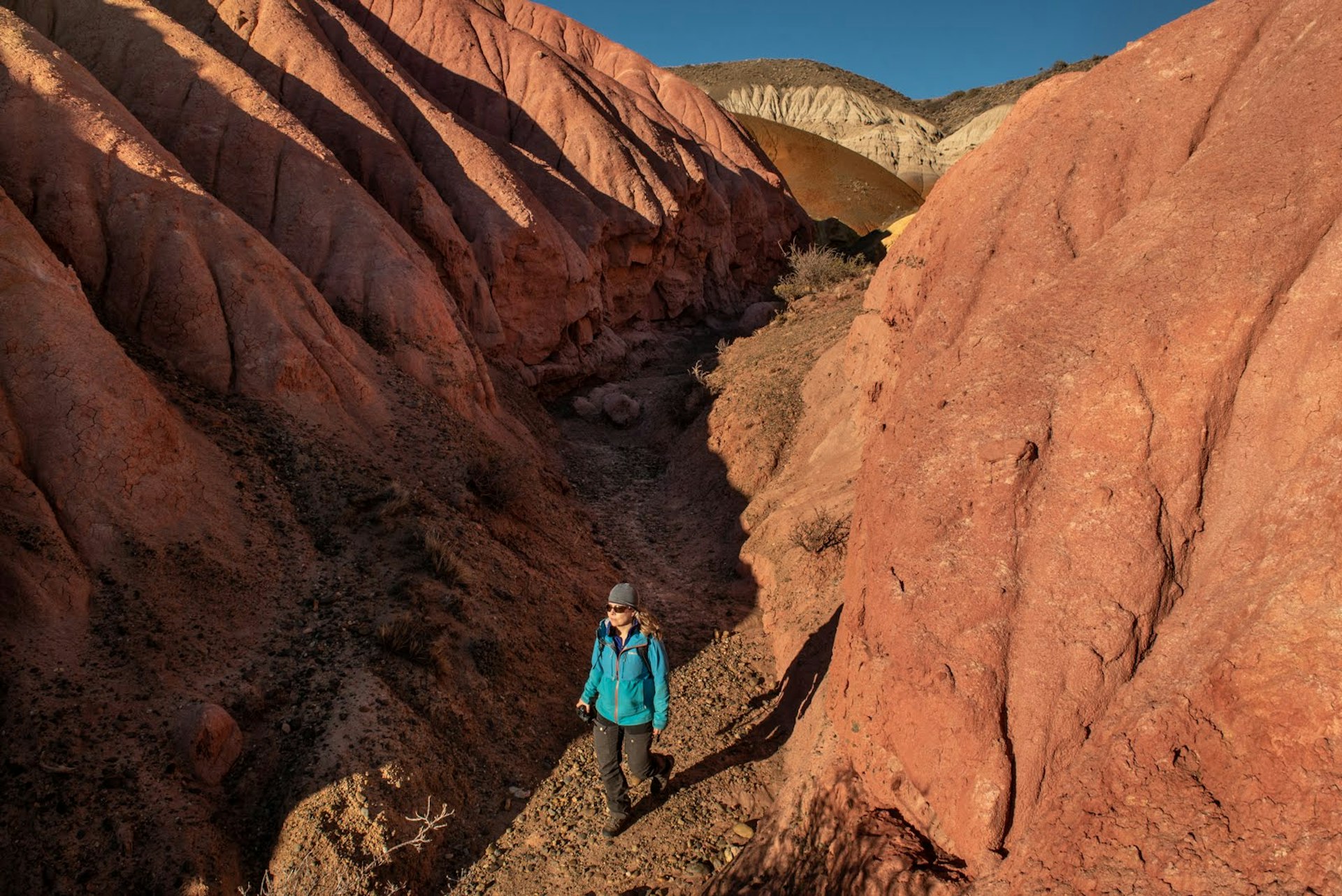 A hiker surrounded by a short canyon of red rock walls in Argentina's Patagonia National Park