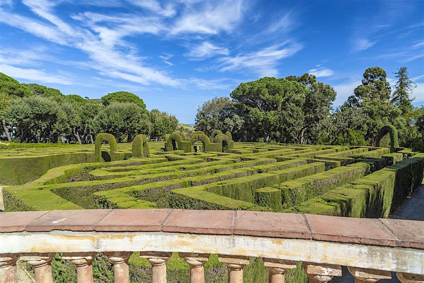 Features - horta-barcelona-dd2c65e8bec9 Looking over a pillared wall to a cypress hedge labyrinth below, with trees beyond.