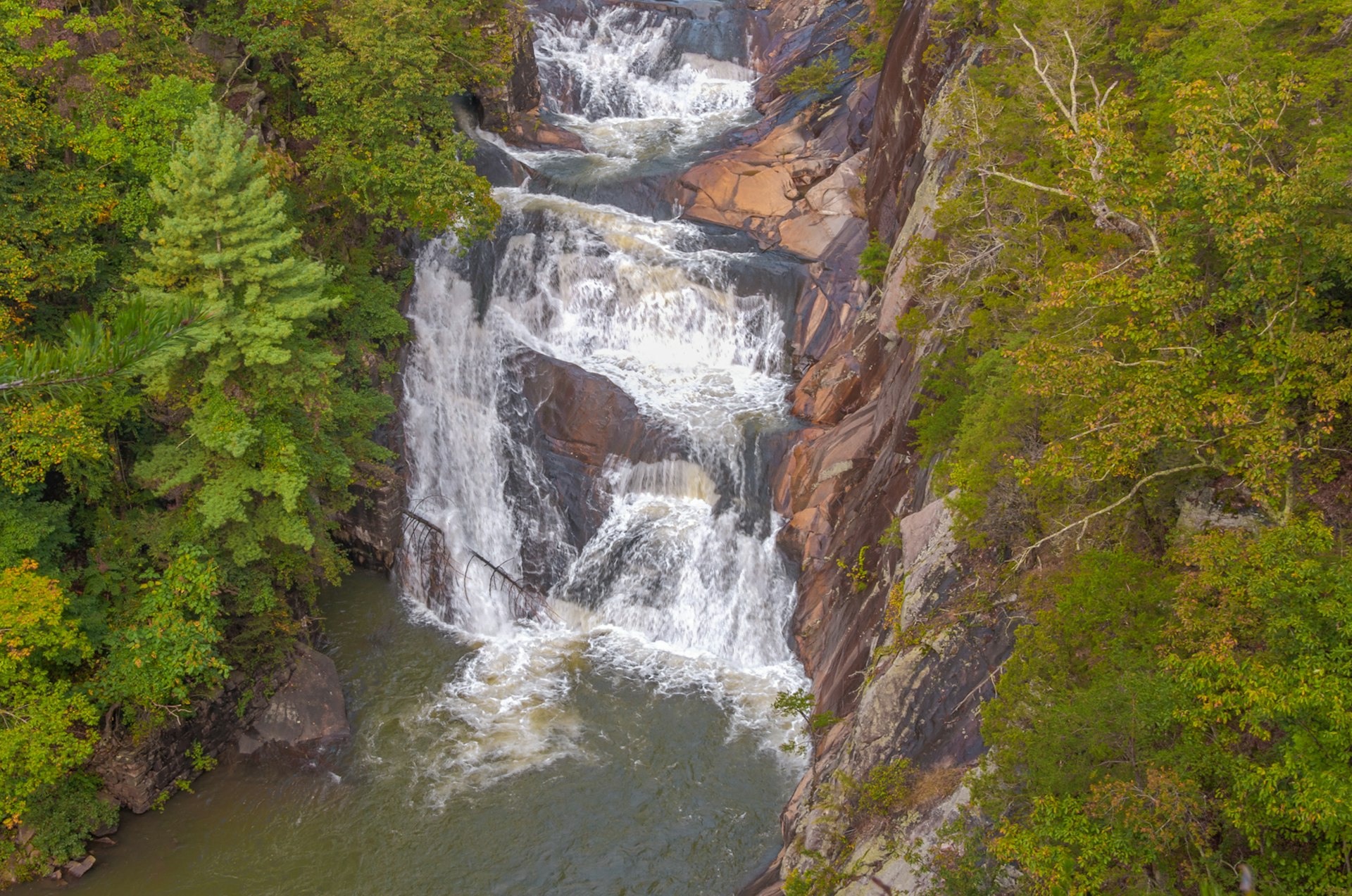 An overview of a waterfall framed by green trees; summer trips in the Southern US