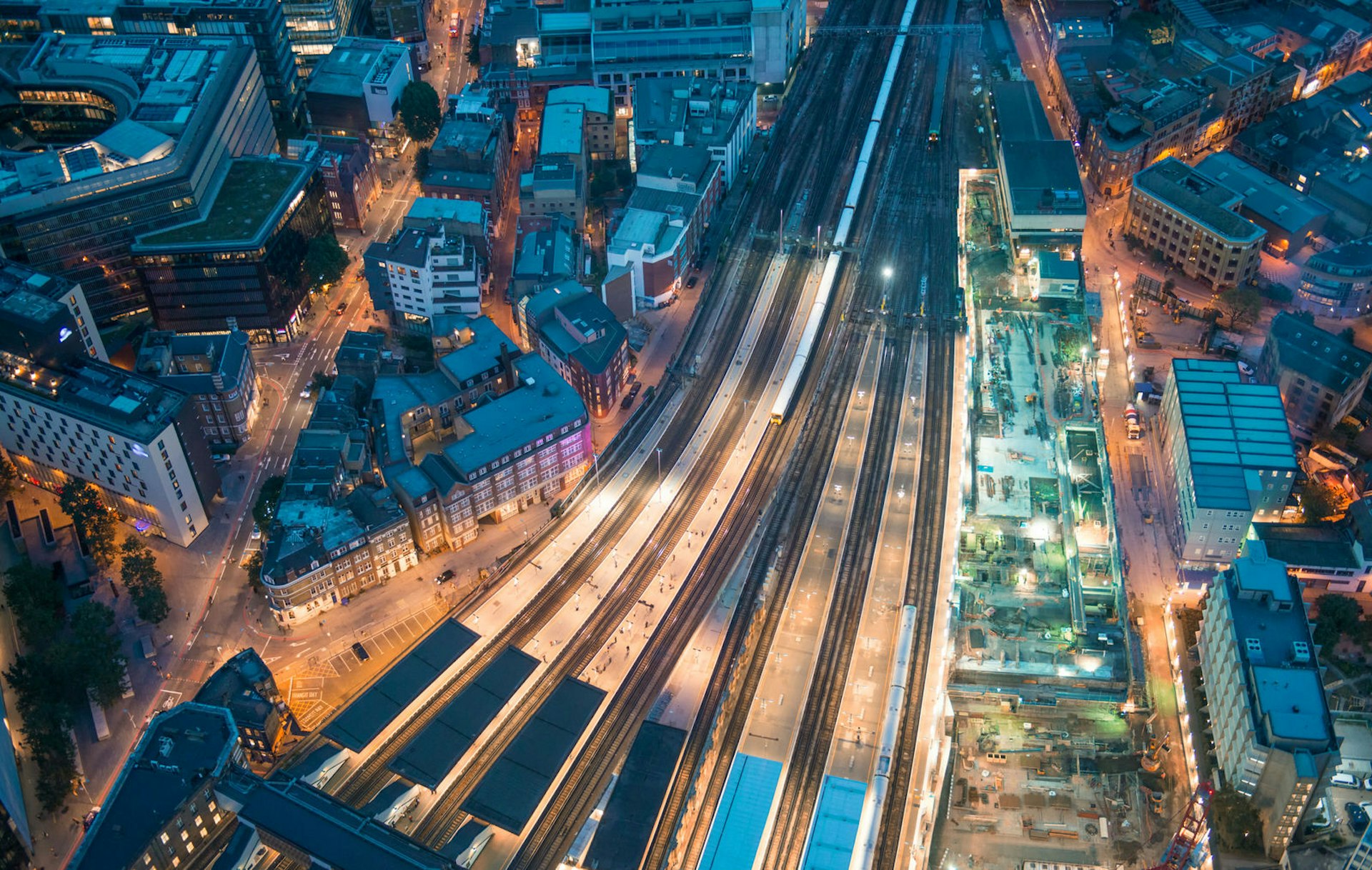 An aerial shot of Euston train station in London at night with two trains leaving the station