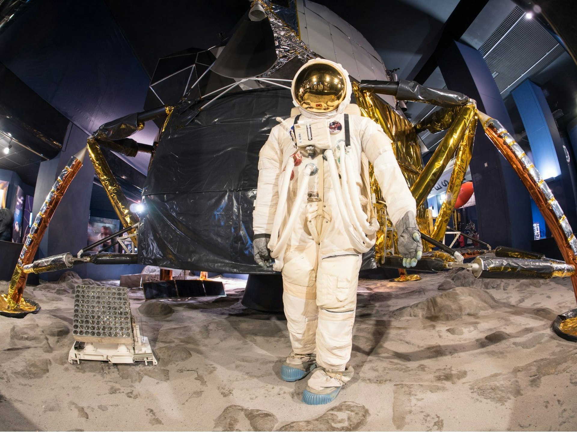 An astronaut stands near a module on the moon in an exhibit on space travel