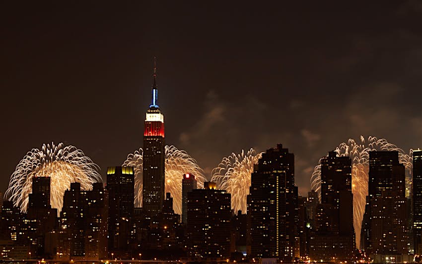 与烟花的纽约地平线在它后面的烟花在7月4日与被点燃的红色，白色和蓝色的帝国大厦;7月最佳庆祝活动中最佳庆祝活动