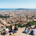 Teens sit on the viewpoint with a view of the city of Barcelona stretching off into the distance