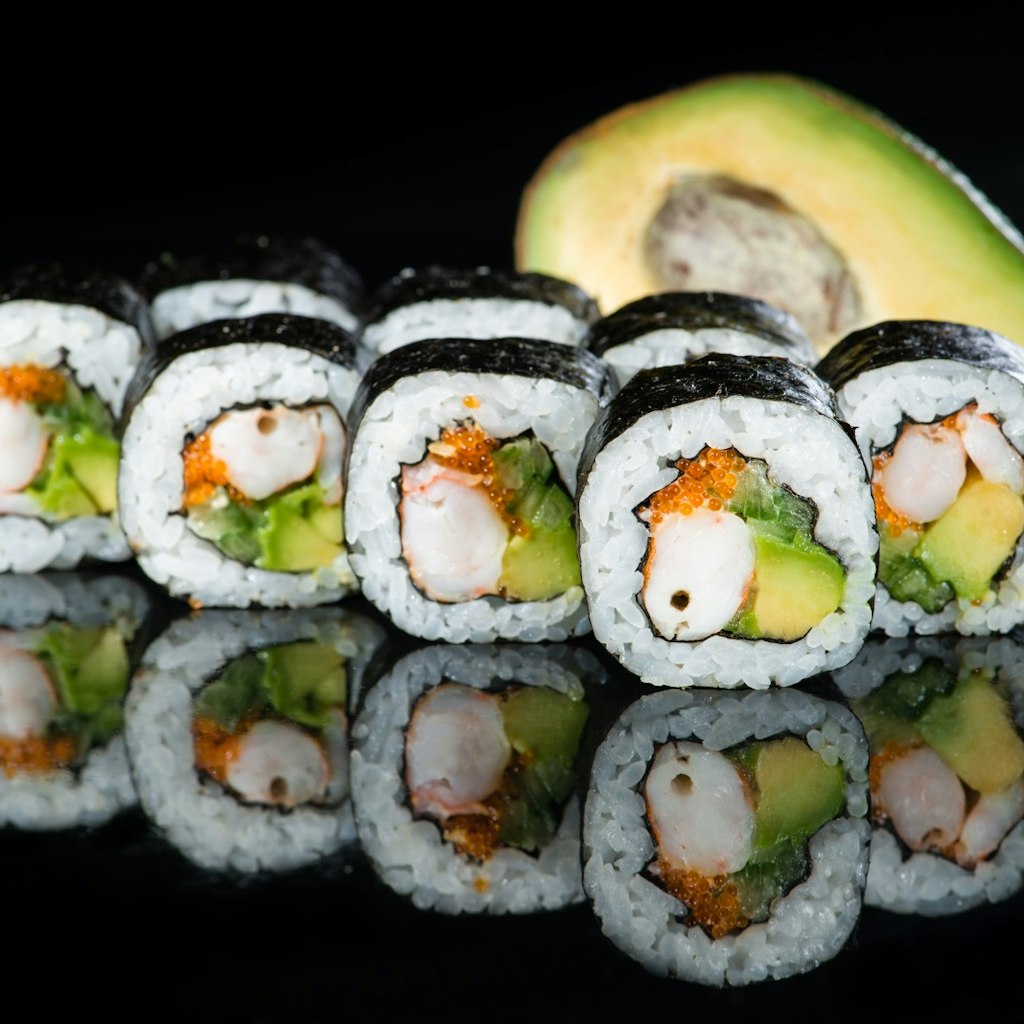 Fresh delicious Japanese sushi with avocado, cucumber, shrimp and caviar on dark background
