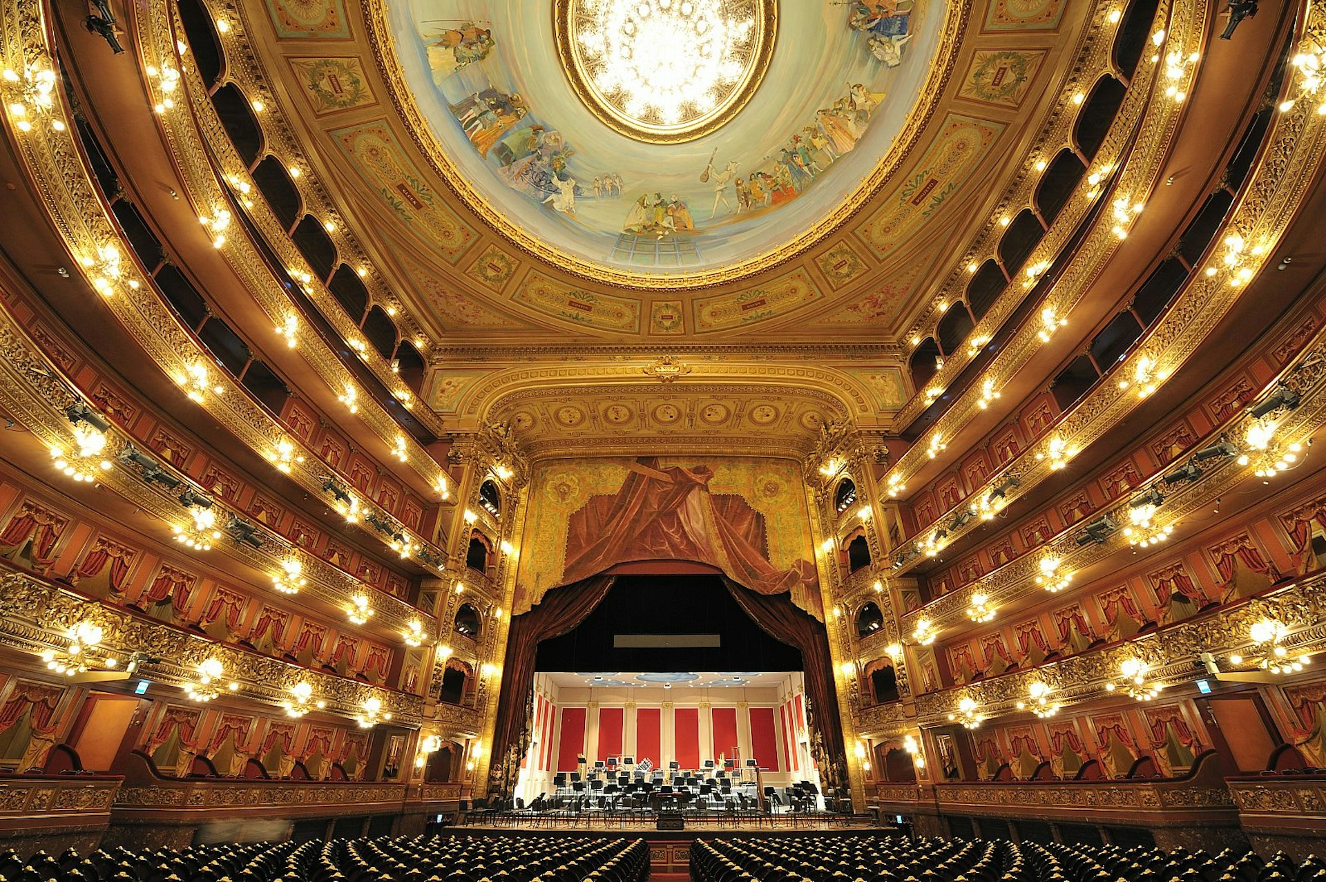 The opulent interior of Buenos Aires' Teatro Colón; we look towards the ornate, gilded stage, which has a frescoed ceiling above; either side of the theatre is lined with rows of handsome balconies containing boxes.