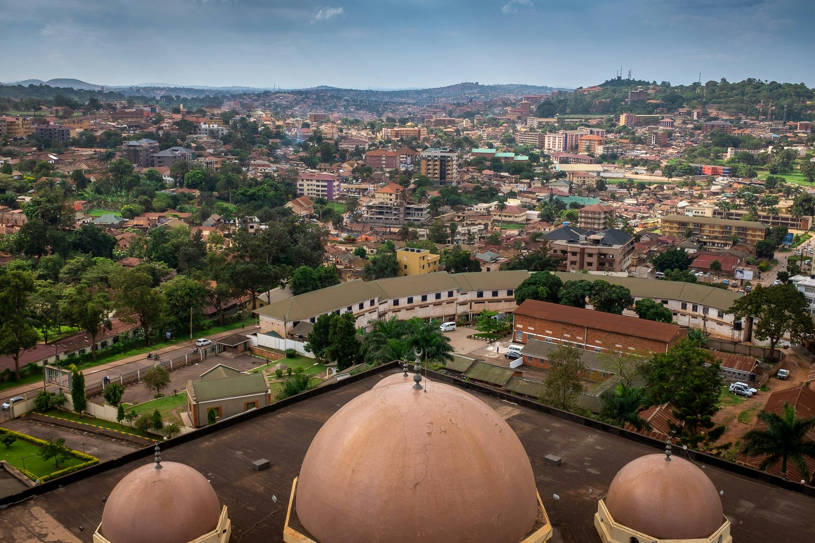 Looking down over three domes (the biggest in the middle, flanked by two smaller ones) atop the Old Kampala National Mosque; in the distance below are the red roofs carpeting the hills of Kampala