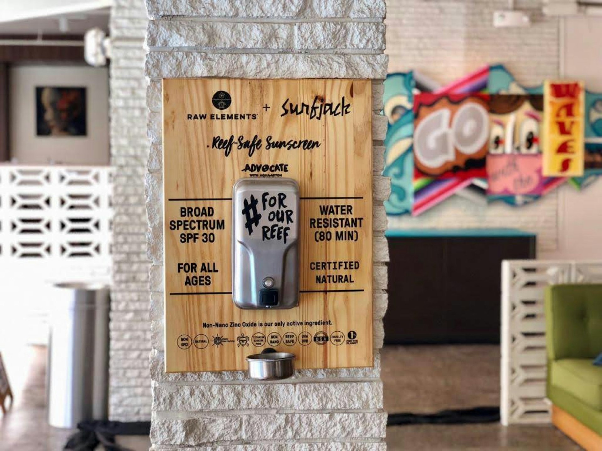 A wooden sign and dispenser offers free reef-safe sunscreen on the wall of a hotel in Hawaii
