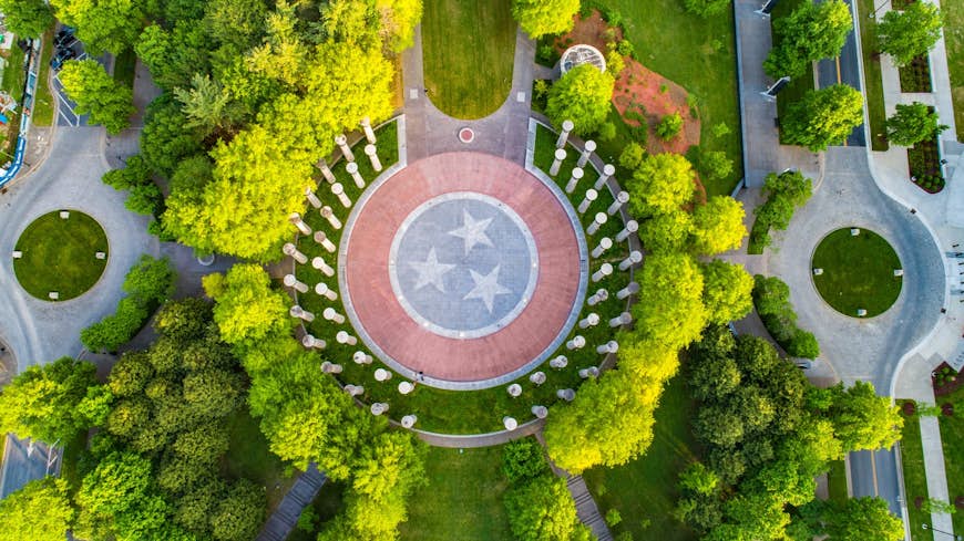 Aerial view of a Bicentennial Capitol Mall with trees and tall pillars. In the middle is circle stone with the Tennessee flag emblem painted on it; weekend Nashville 