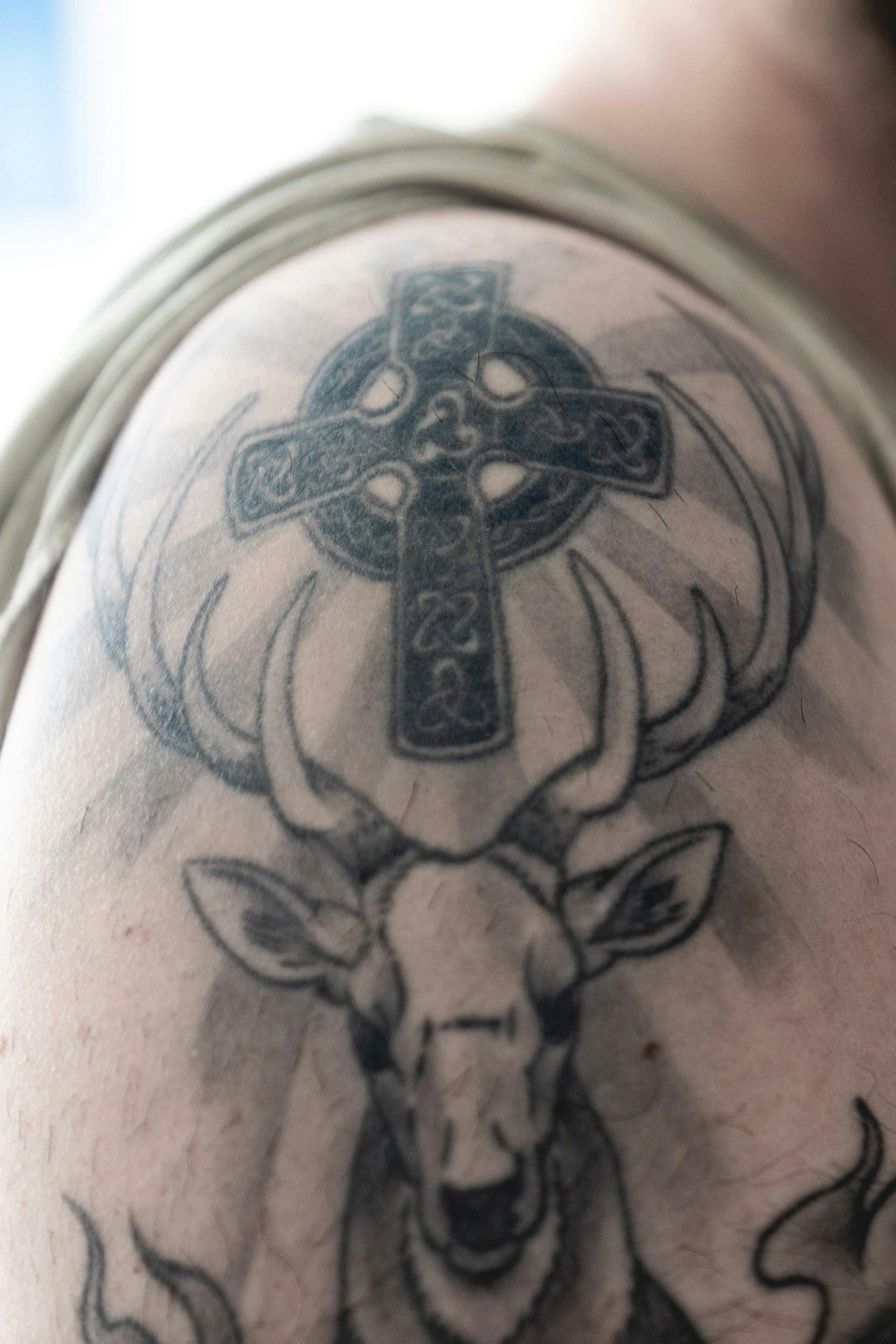 A celtic cross with knotwork on a person's shoulder and upper arm