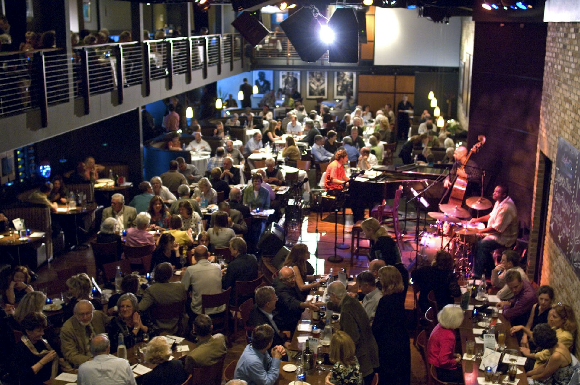 Interior of the Dakota Jazz Club and Restaurant, which is packed with people sitting at tables while a live band plays on an elevated stage
