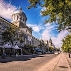 The Bonsecours Market of Montreal sits along a cobblestone street on a beautiful clear day
