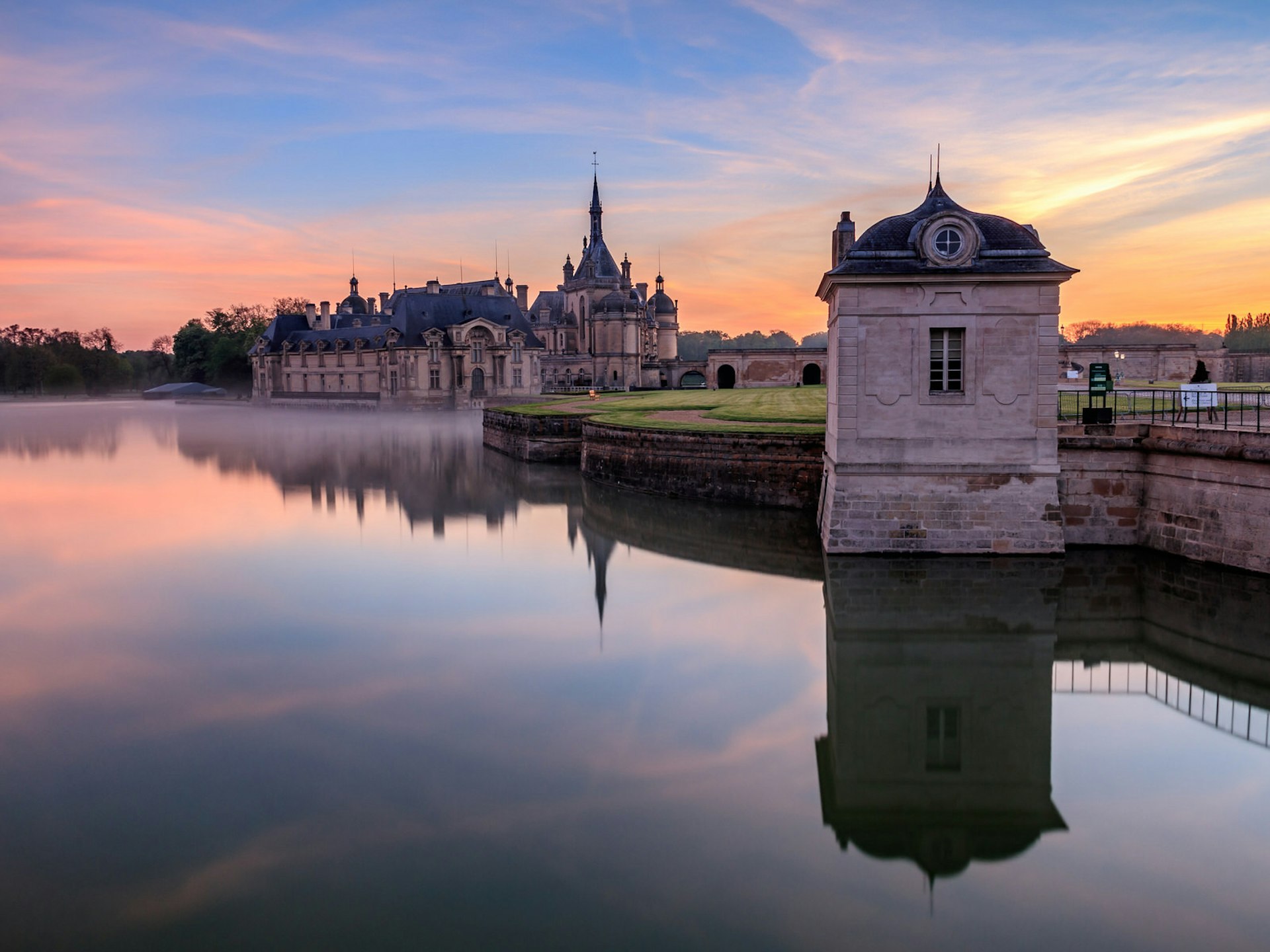 The Château de Chantilly: a large mansion rising from an artificial lake, photographed here at dawn.