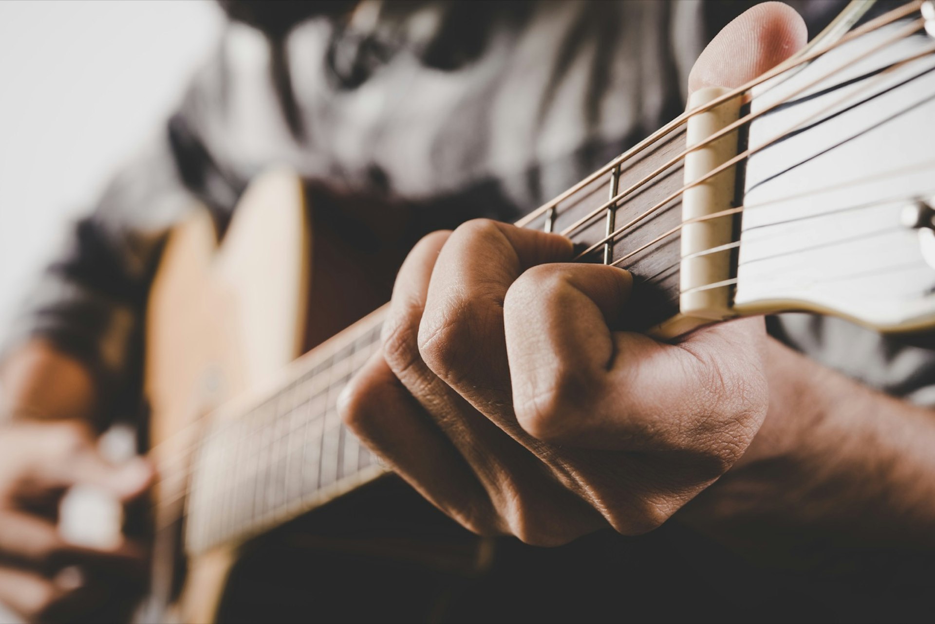 Närbild av ett par händer som spelar en akustisk gitarr;  helgen Nashville 