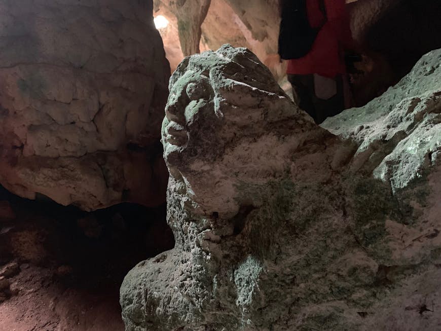 A head and face carved out of stone inside of a cave; Long Island Bahamas 