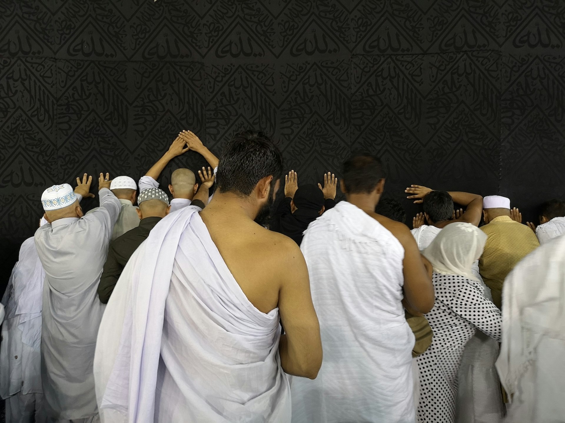 A group of people worshipping at the Kaaba, most are dressed in white and all are facing towards the Kaaba in worship. Hajj diaries