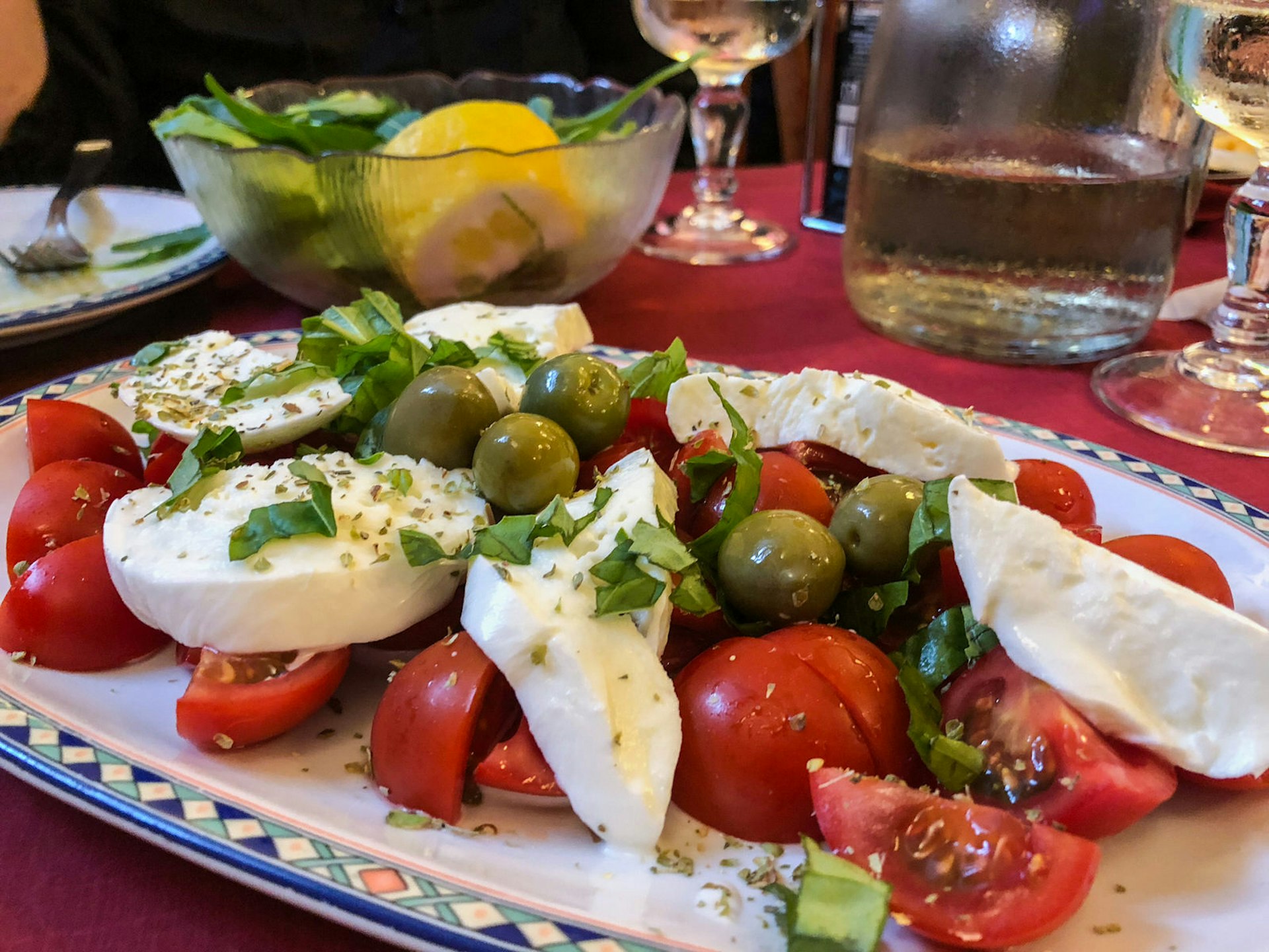 Caprese Salad with mozzarella cheese, tomato, basil and olives on table at Island of Ischia, Campania, Italy.
