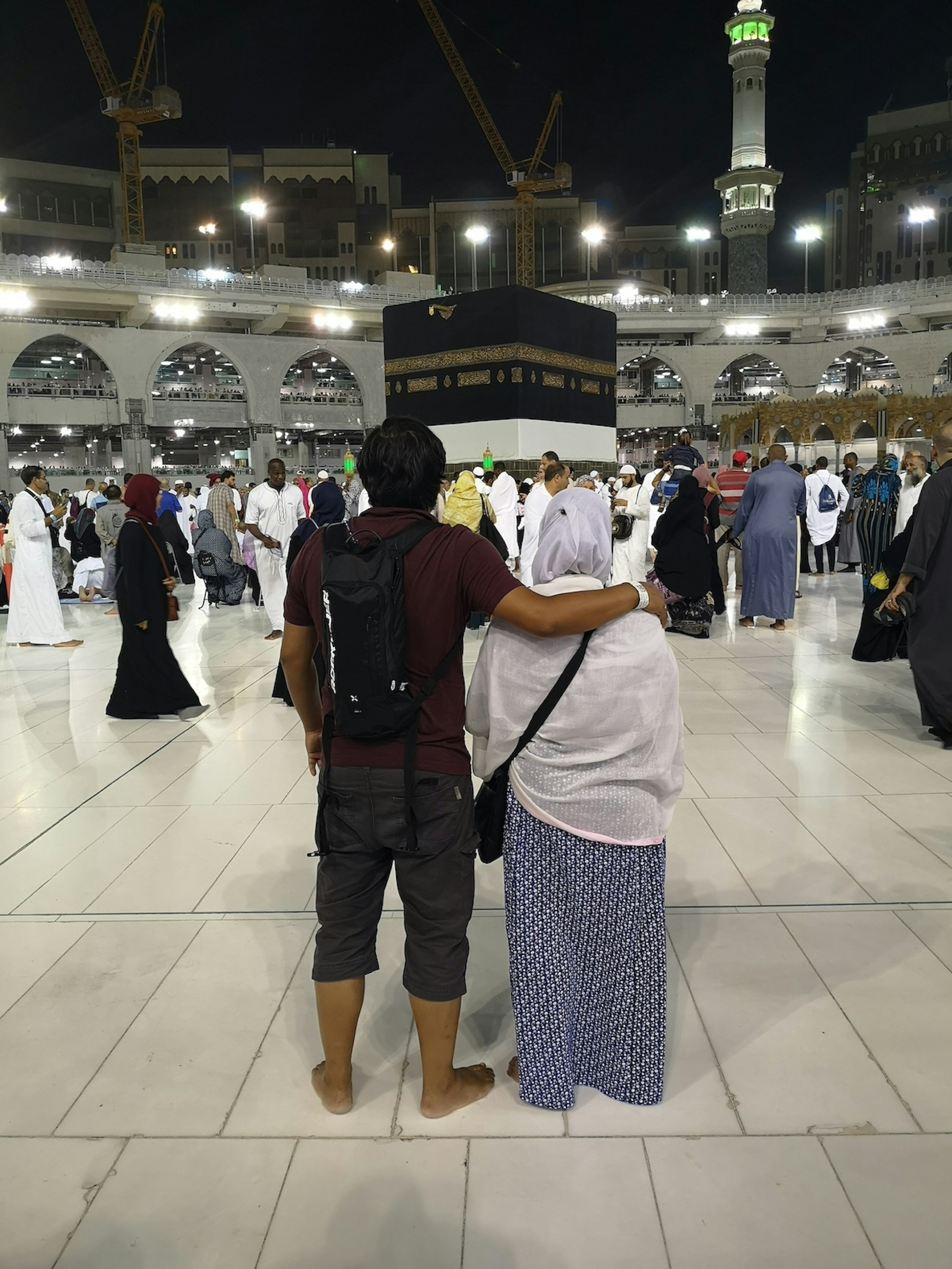 Tharik and his mother stand facing away from the camera and looking towards the Kaaba at the centre of the image. Tharik's arm is around his mother's shoulder. Hajj diaries