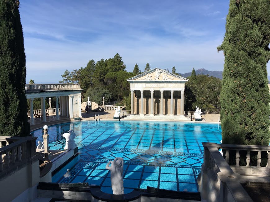 The facade of an ancient greek temple is seen across the sparkling blue water of the pool at Hearst Castle in San Luis Obispo