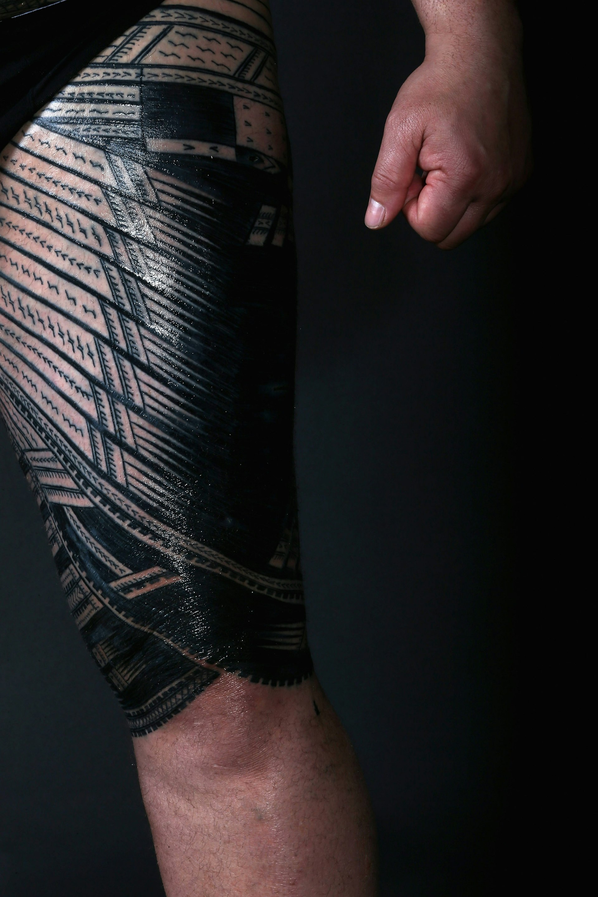A a traditional Samoan Pe'a tattoo covering the entire thigh of a standing person.