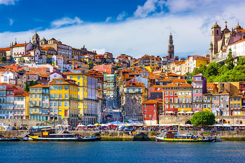 Features - Torre-dos-Clérigos-shutterstockRF_259699643-9556eaa292d0 Looking across the River Douro, the colourful buildings of Porto's old town climb up a hill; bursting from the top of the hill is the large tower of Torre dos Clérigos; attending a concert across the street from the tower is one of the best free things to do in Porto