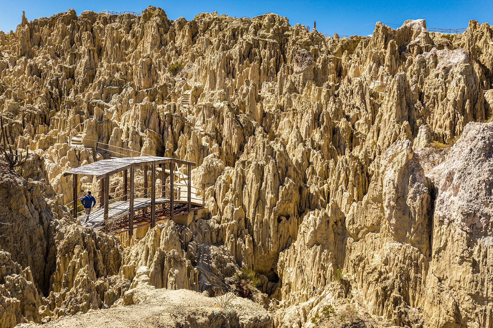 En person korsar en skogsbro bland taggiga geologiska formationer i Valle de la Luna.  La Paz, Bolivia.