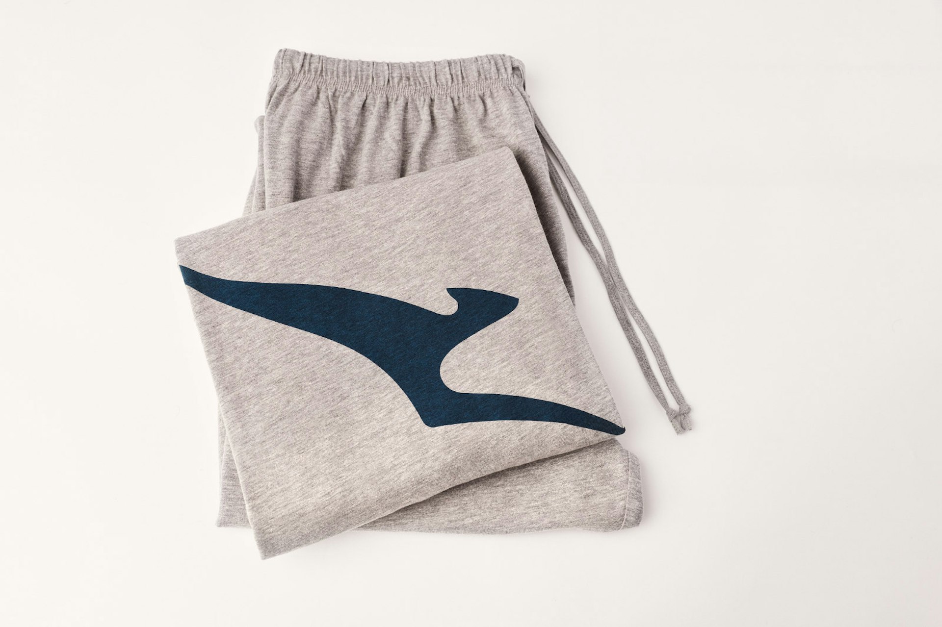 A grey pyjamas bottom and top, folded up, showing a flying kangaroo silhouette logo