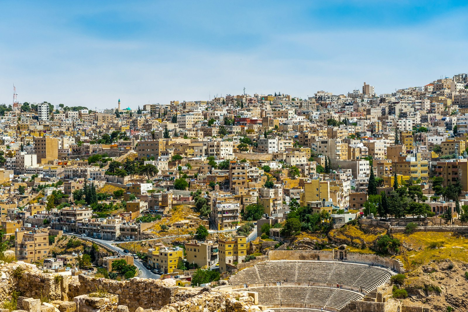 In front of the city that seems perched on a hillside is the Roman Theatre, with its semi-circular seats arching around its centre stage; Free things to do in Amman, Jordan