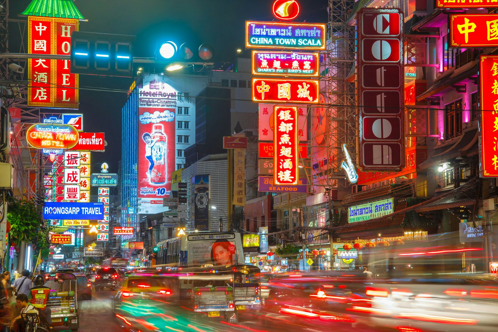 Traffic on Yaowarat Road passes below neon-lit signs in the Chinatown district at night. 