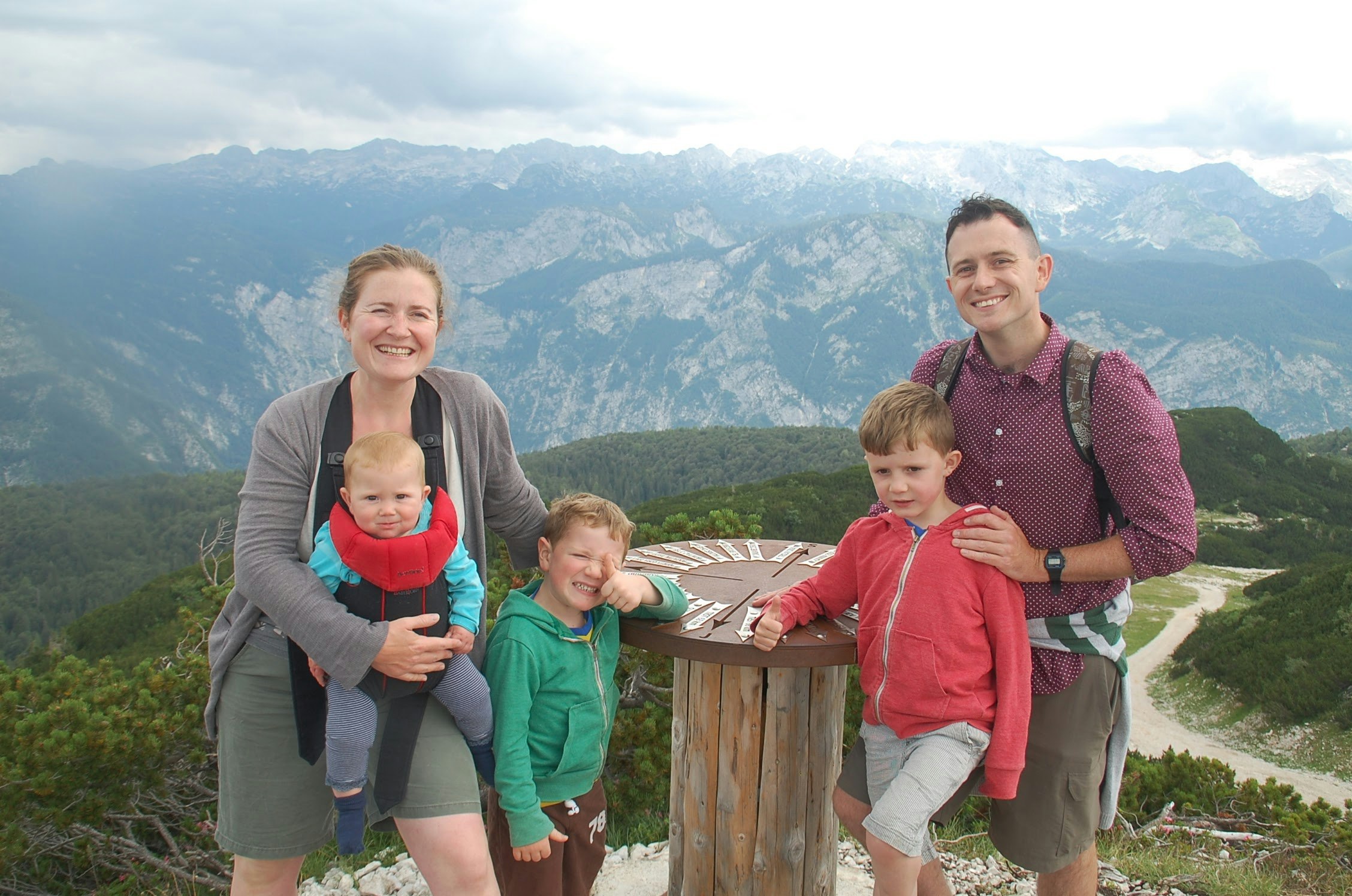 Imogen, her baby and two older children with husband Tom on top of an alpine mountain.
