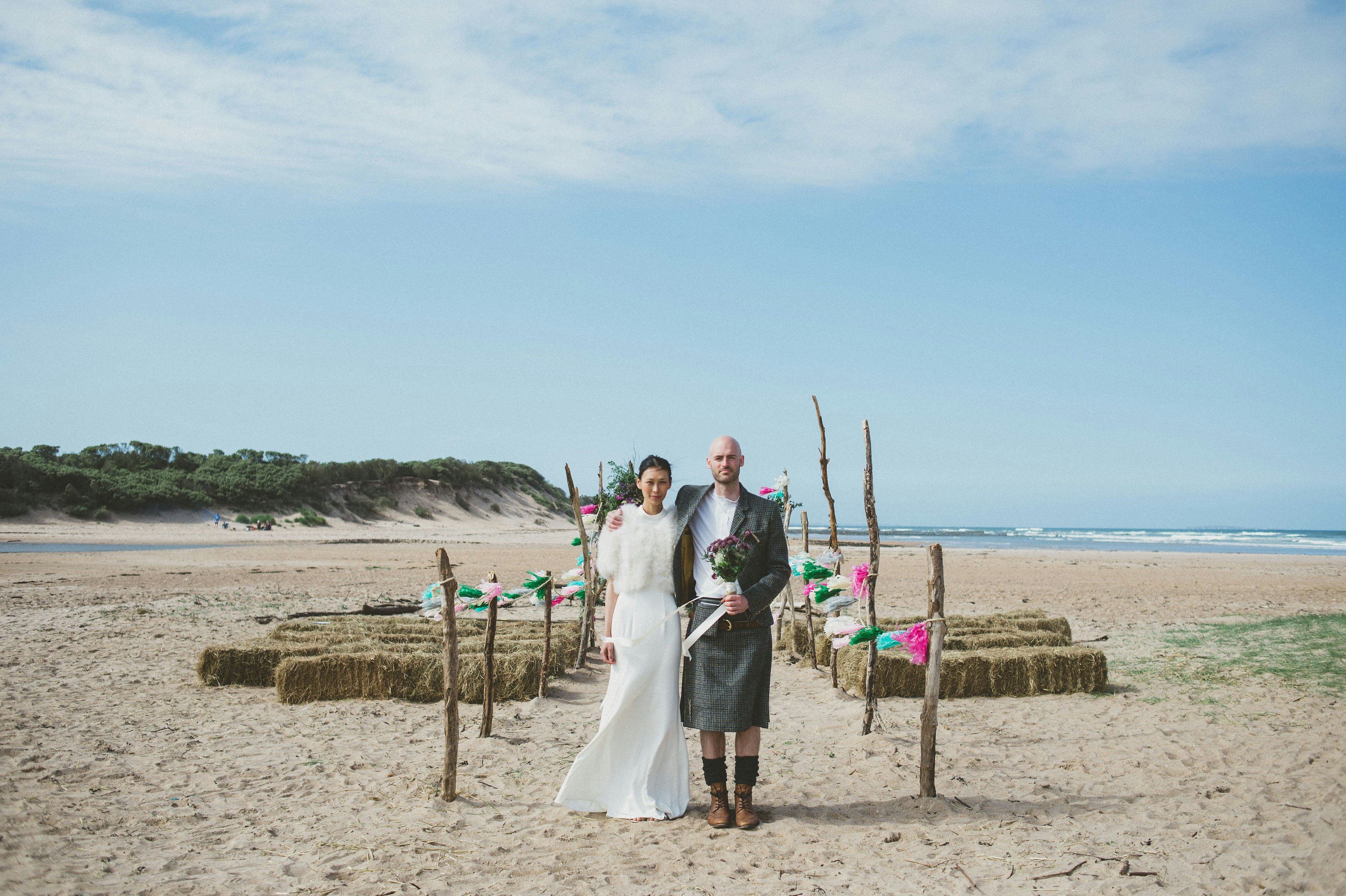 A bride and groom pose on the beach at Harvest Moon, East Lothian