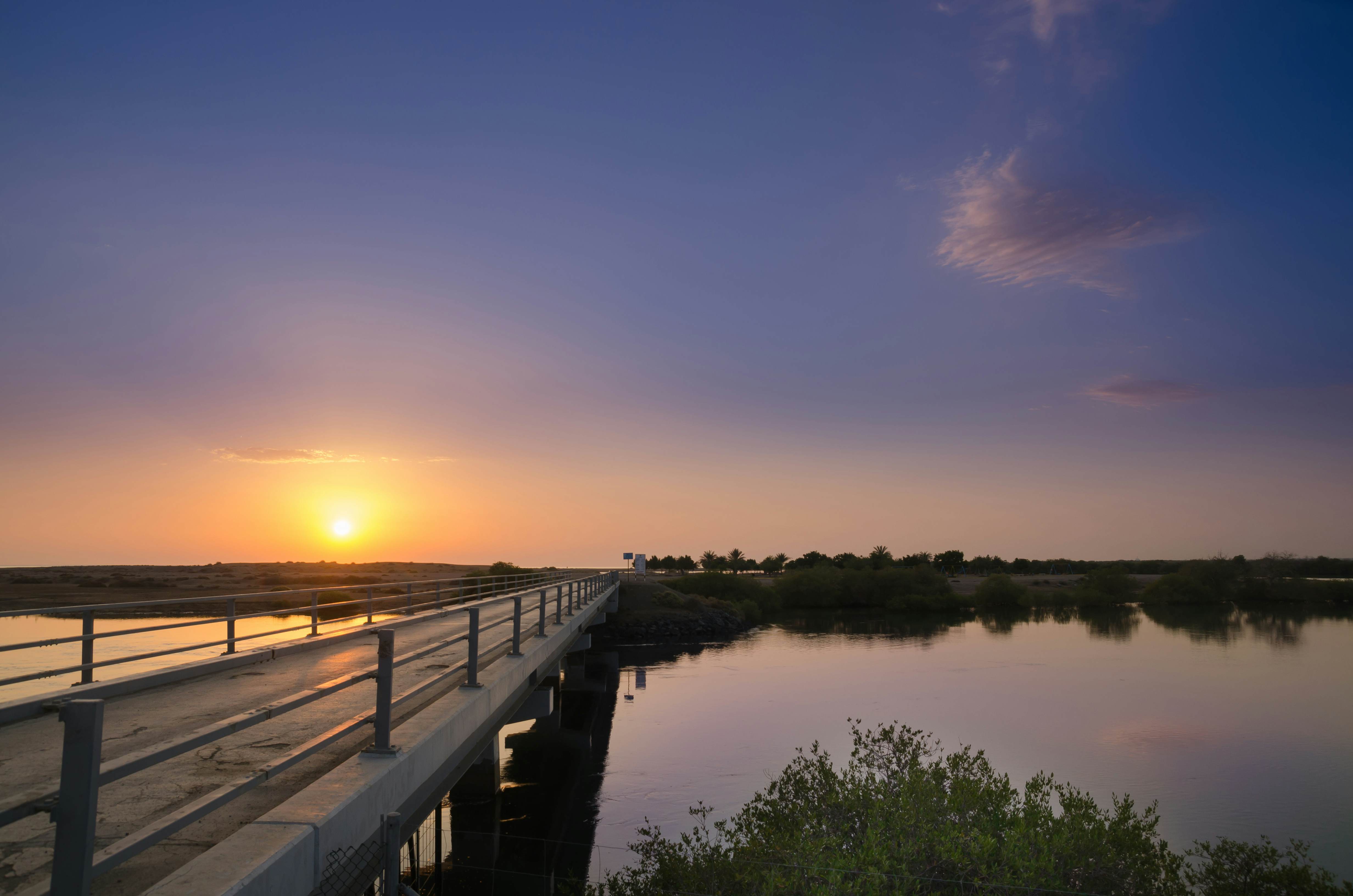 The Kalba Bridge stretching across periwinkle water at sunset