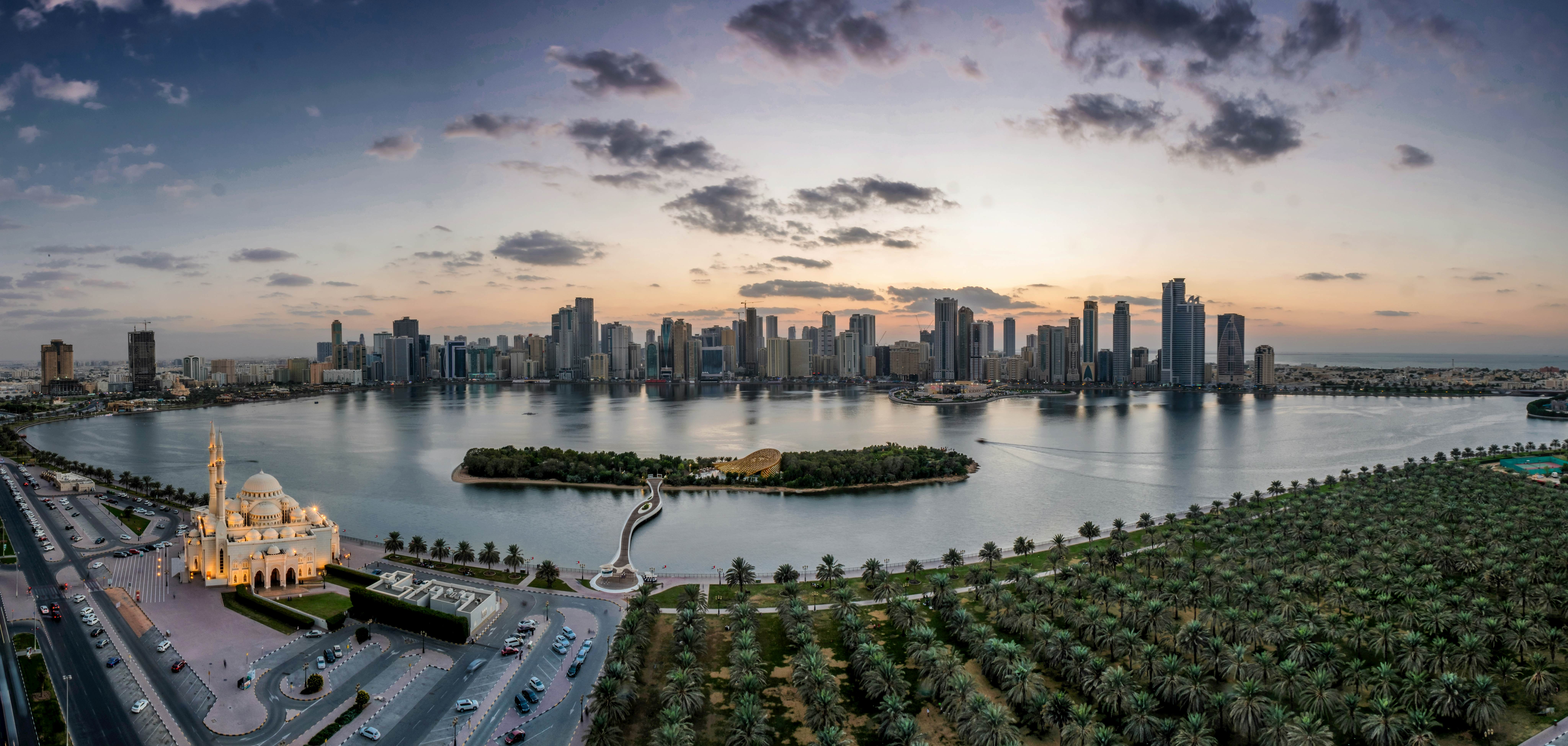 The Sharjah skyline at dusk reflecting off the water with the grand Mosque lit up in the foreground 