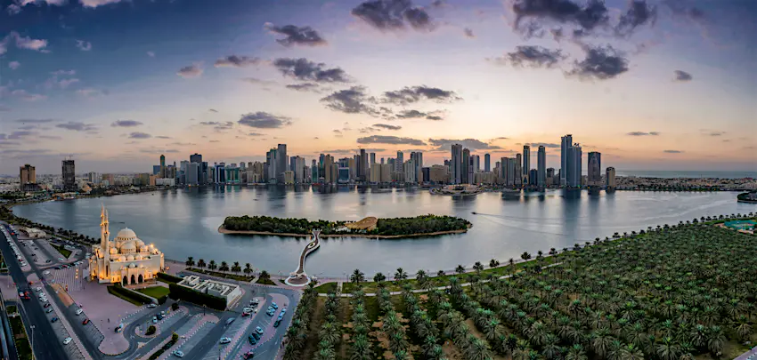 Sharjah The Sharjah skyline at dusk reflecting off the water with the grand Mosque lit up in the foreground