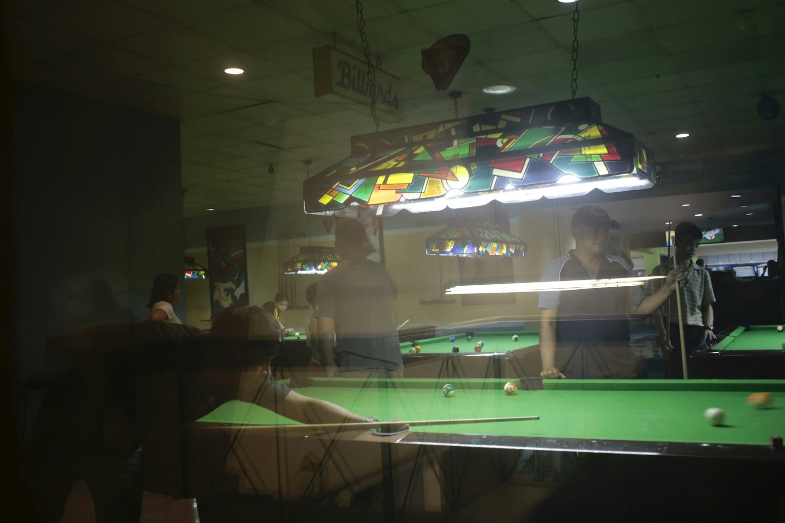 View through the window of men playing billiards, 80s decor inside