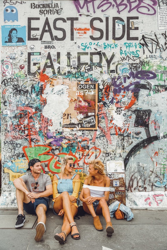 Young people sitting against a graffitied wall.jpg