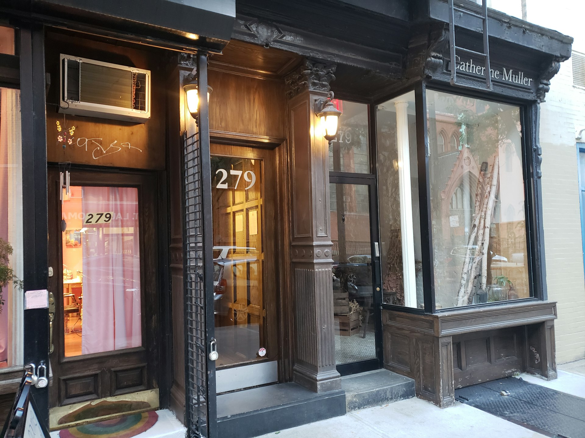 The exterior door to the apartment where Mike Viola once lived is a mix of architectural styles, with wood grain paneling on the exterior, square Corinthian columns, metal security gates, and glass windows.