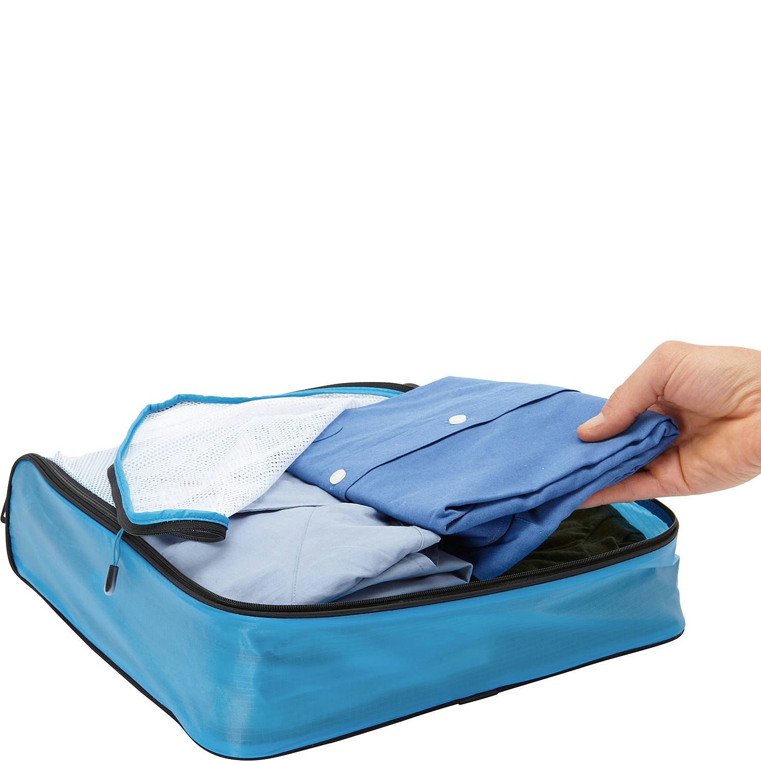 A blue travel packing cube filled with folded clothing sits against a white background with its white mesh cover partially unzipped. A white male hand reaches into the bag to lift a button-down shirt.