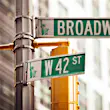 Street signs reading the intersection of 42nd St and Broadway