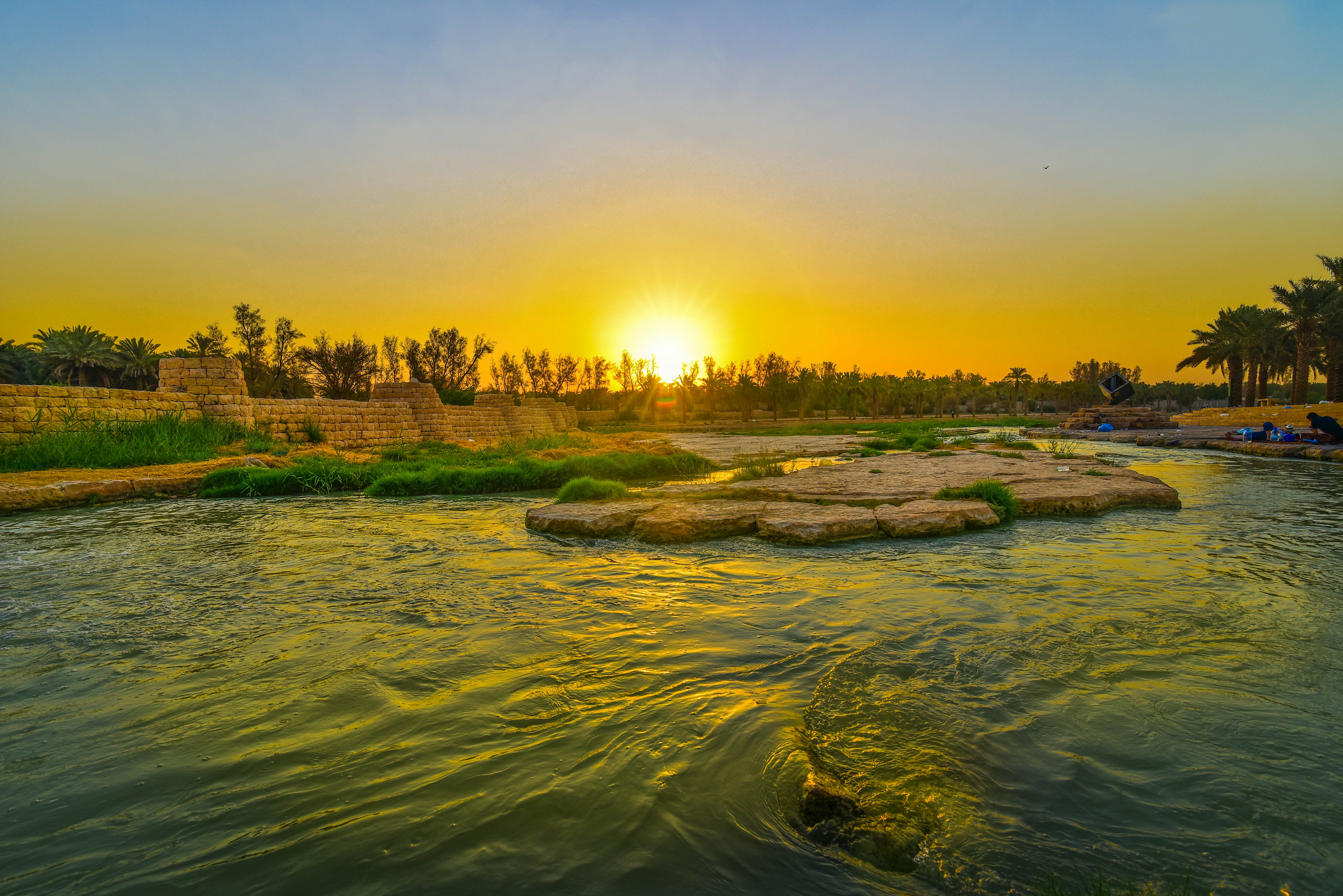 Water and a greenery-filled valley with the golden sun setting in the background
